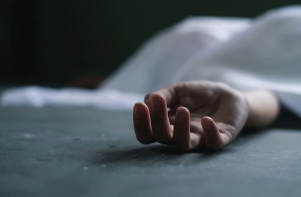 Deceased person’s hand outstretched against a dark background