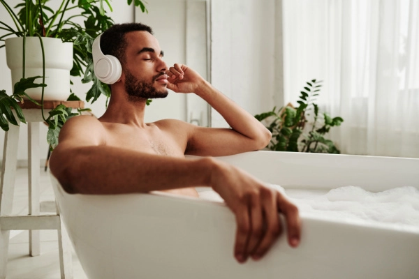 Man going through kratom withdrawal sits in the tub and listens to calming music to help alleviate symptoms