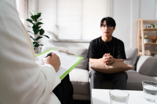 Young man talks to therapist who takes notes during the session