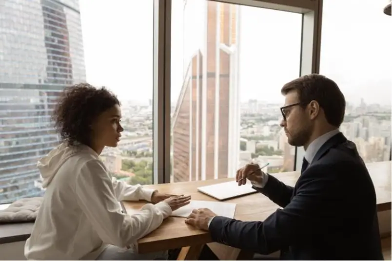 Employee talking to manager in an office with city views outside